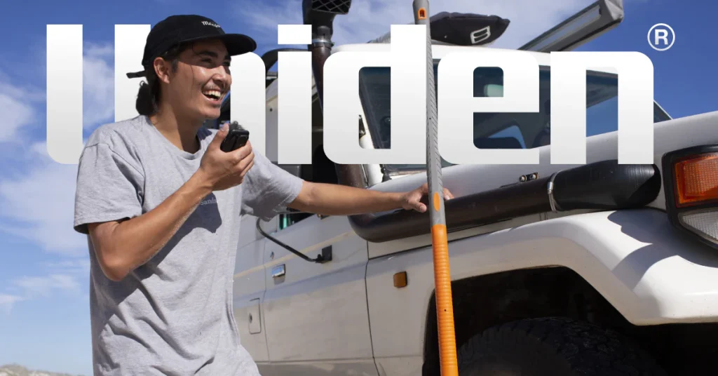 Uniden campaign image of a person using a handheld radio beside a four-wheel drive