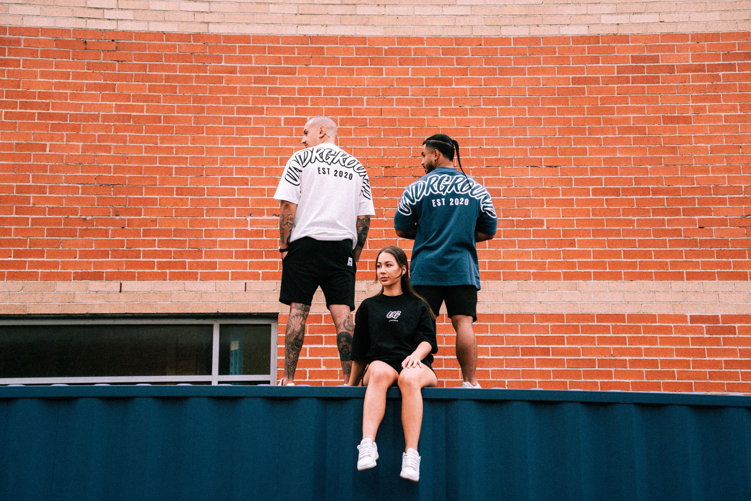 Three UNDRGROUND campaign models posed against a brick wall