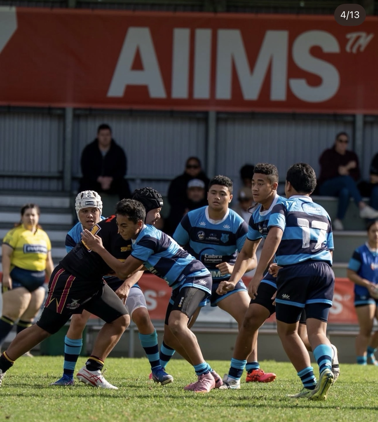 Cabramatta Two Blues players on the field with AIIMS stadium signage behind them
